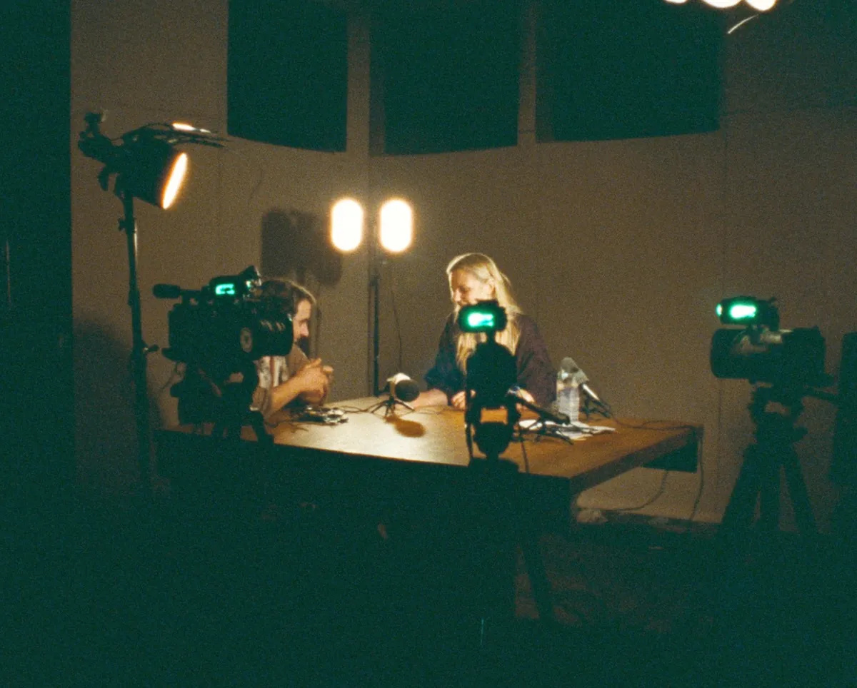 Two hosts recording a podcast under soft lights
