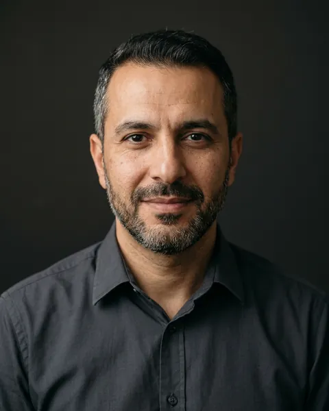 AI-generated portrait of Brian, a middle-aged Middle Eastern man with short dark hair, a trimmed beard and a dark collared shirt, smiling softly against a dark grey backdrop.